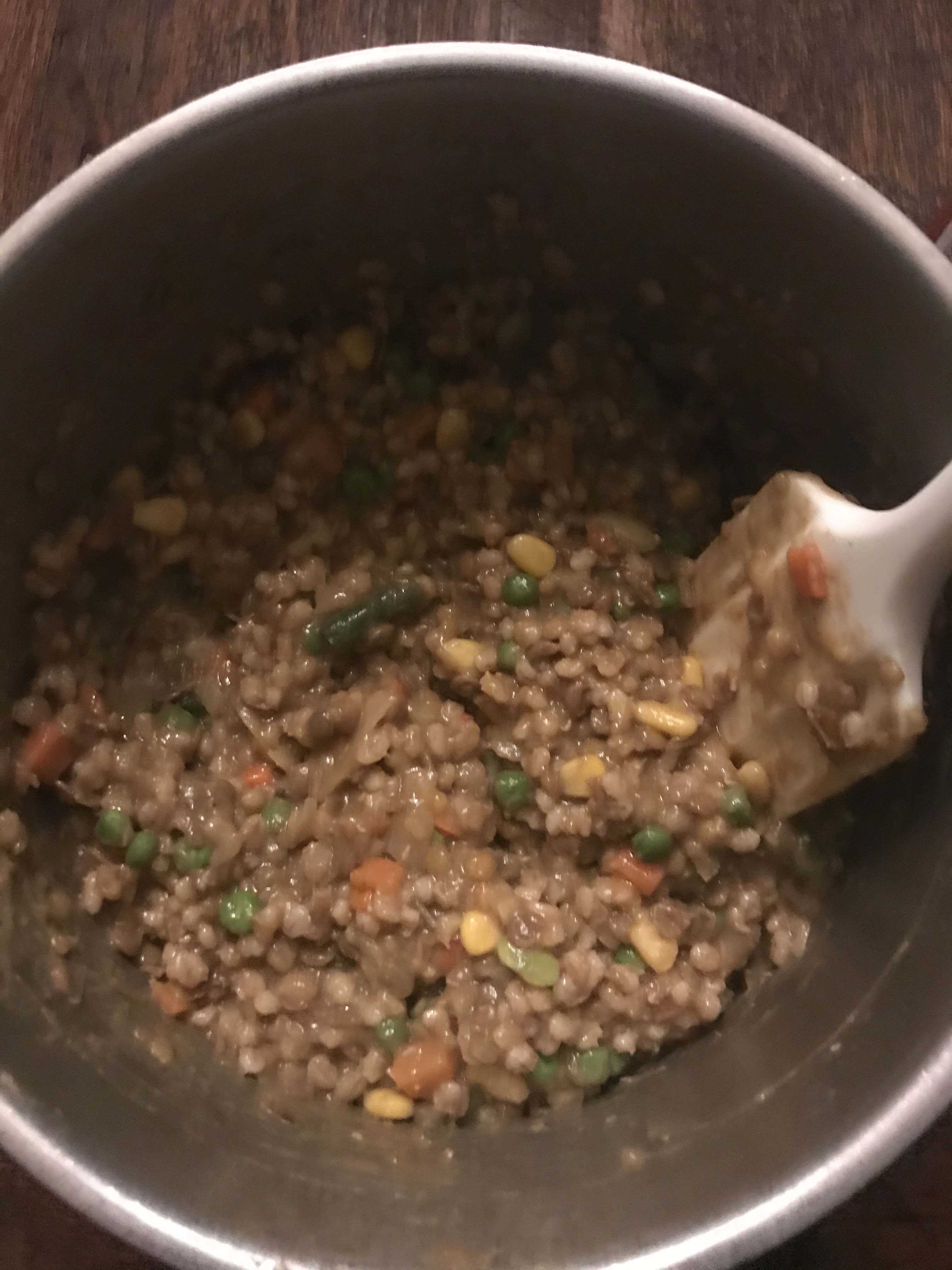 A pot of lentils, barley, and frozen vegetables